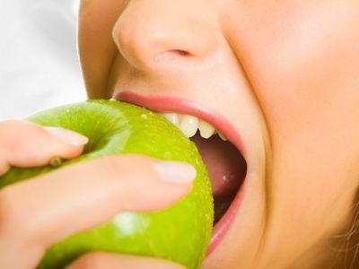 Eine Frau beisst in einen gr&uuml;nen Apfel