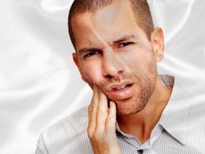 Ein junger Mann, der sich sch&uuml;tzend die Hand auf die Wange gelegt hat