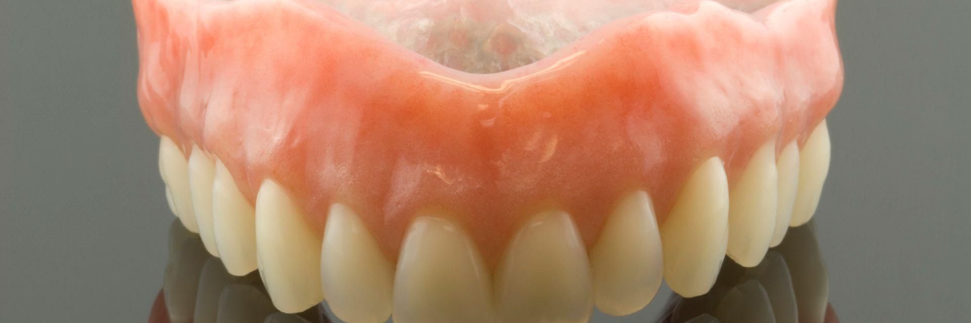 Eine Zahnprothese, die sich in einem Glastisch spiegelt