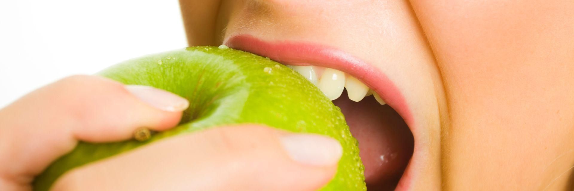 A woman biting into a green apple