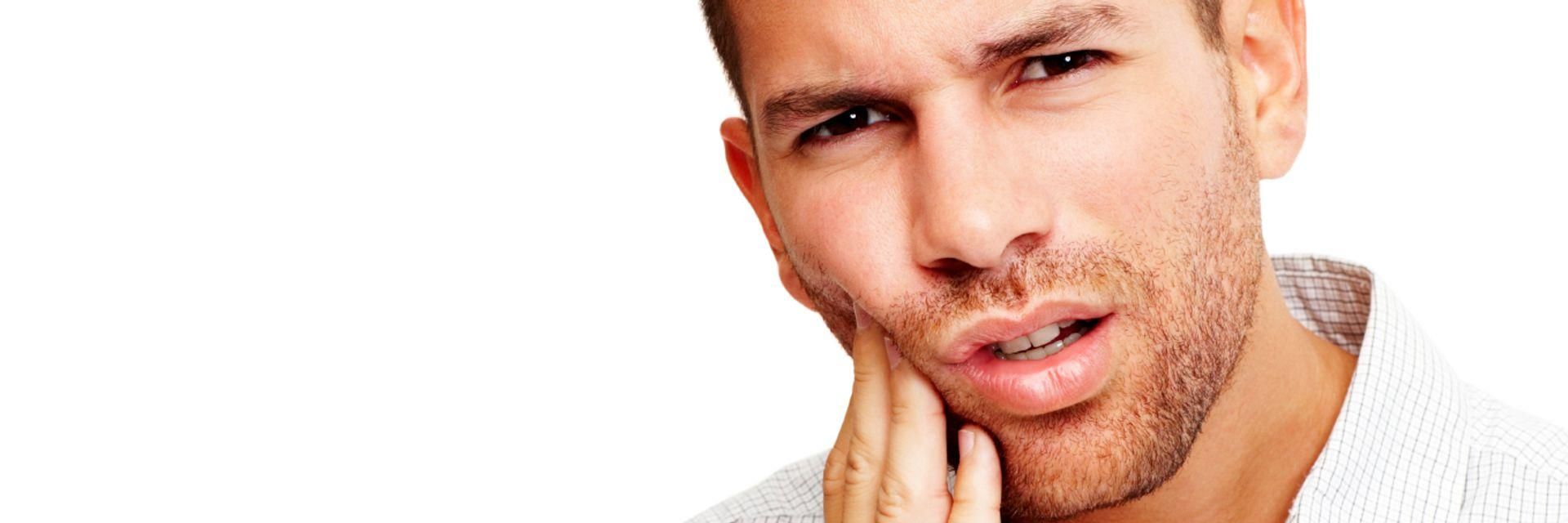A young man protectively placing his hand on his cheek